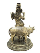 An antique-style brass statue of a Hindu goddess standing on a decorated cow, set against a light gray background.